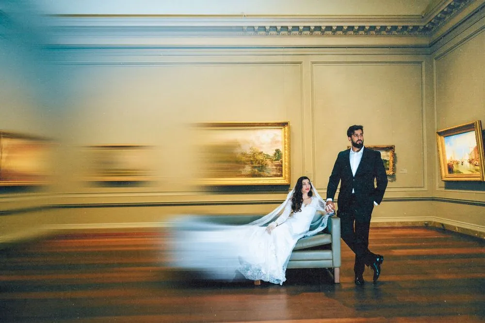 Couple in an art gallery, the bride lying on a bench