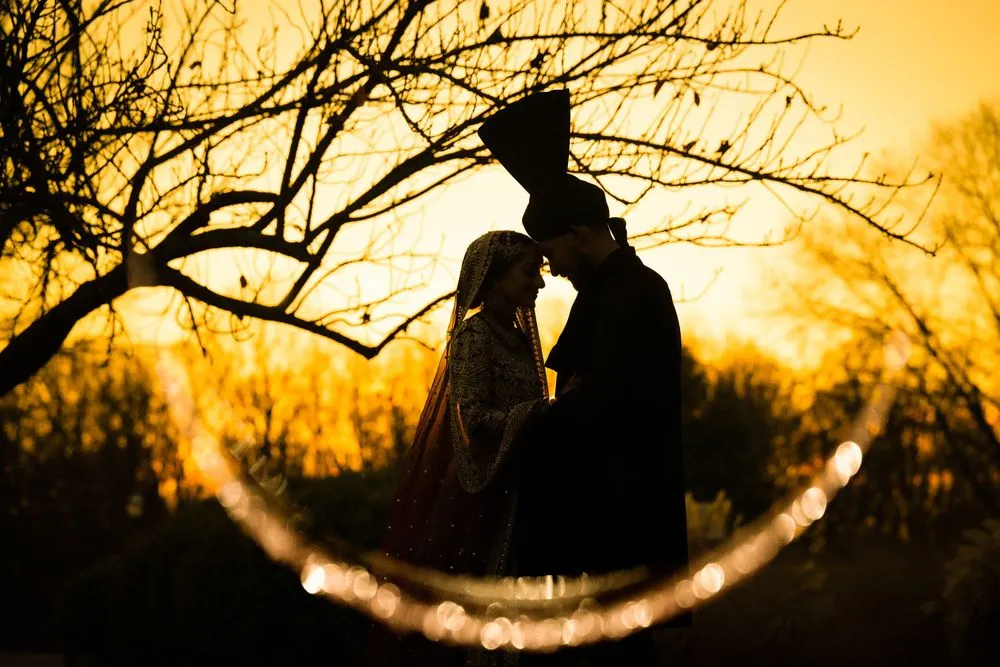 Couple silhouetted against a golden sunset, framed by a ring of light