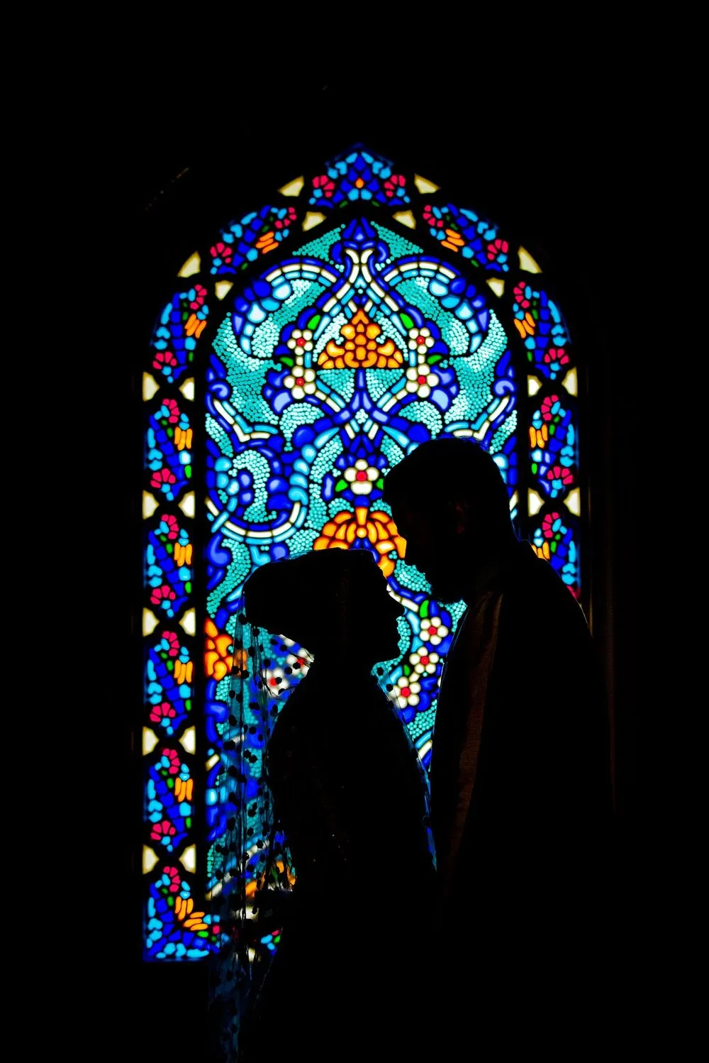 Couple silhouetted against a stained-glass window