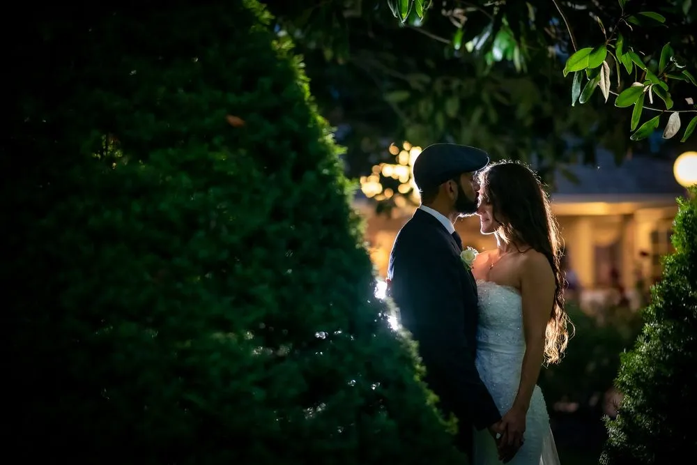Couple embracing in a garden at dusk, lit by warm lights